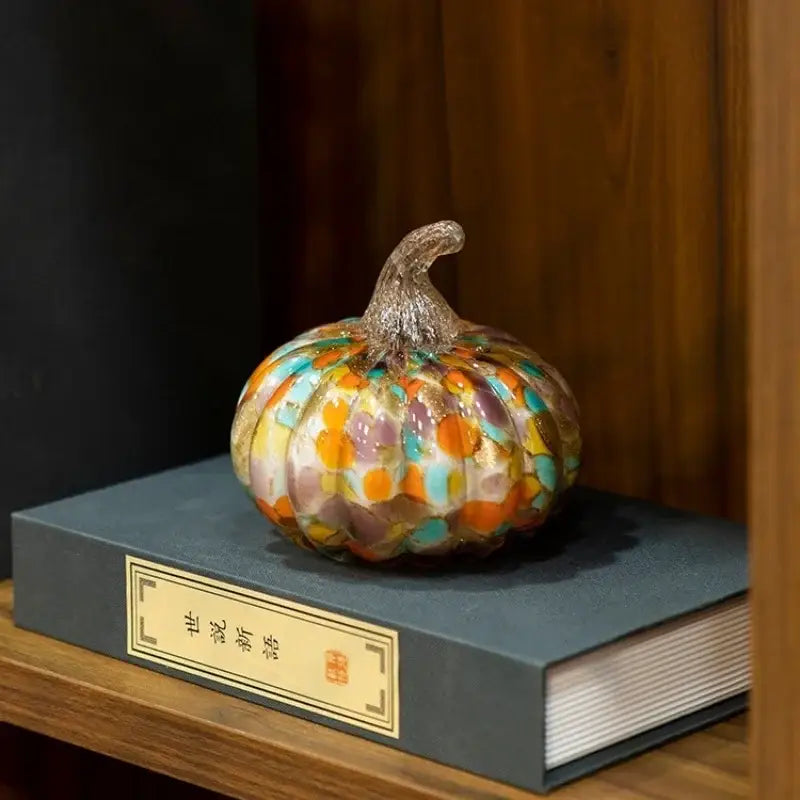A colorful mosaic orange and teal transparent glazed pumpkin sculpture with a glittery stem for home decor