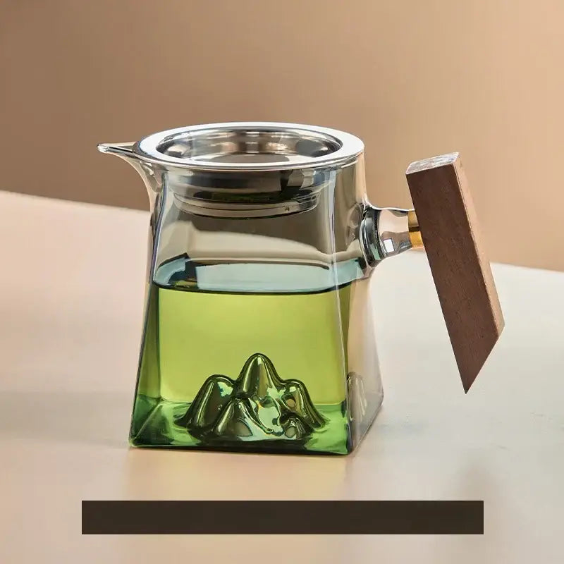 Clear glass tea cup set with silver lid, wood handle, and sculpted mountain base for dining room filter use