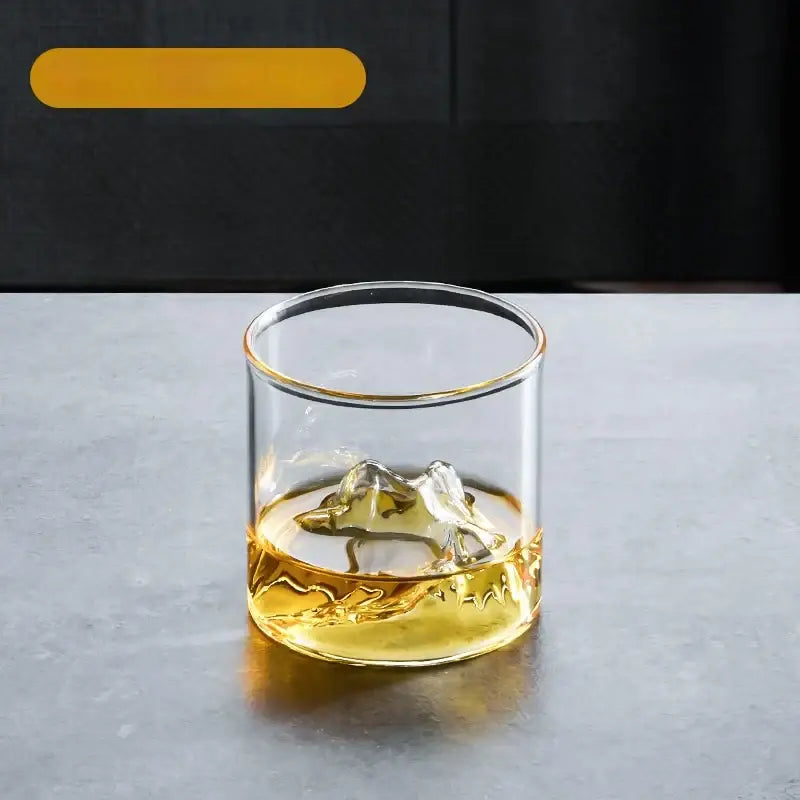 Clear glass tea cup set with gold rim and textured base filled with amber liquid for dining room use