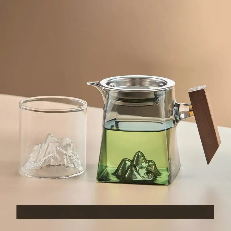 Clear glass tea cup set with wooden handle and metal strainer featuring a sculpted mountain base design