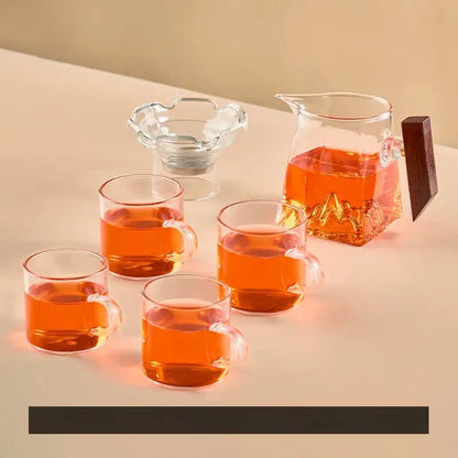 Clear glass tea cup set with dark wooden handle and mountain base filled with amber tea for dining room filter use