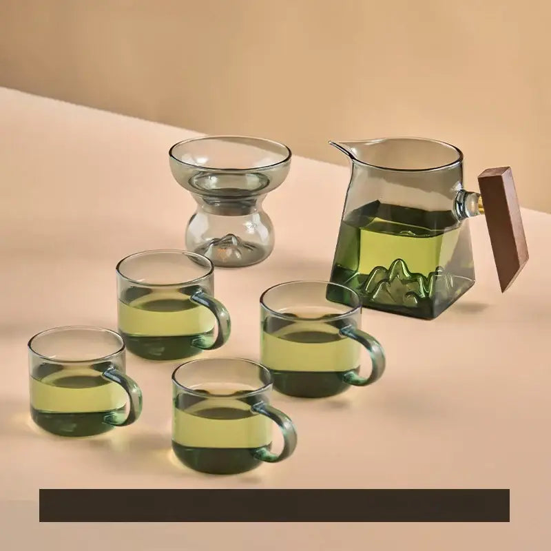 Set of five clear glass tea cups with green tinted handles and a mountain etched pitcher with wooden lid cup set
