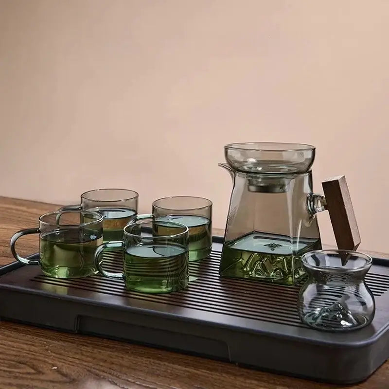 A sleek dark green glass tea cup set with wooden handle and matching ceramic tray for dining room filter use