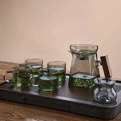 A sleek dark green glass tea cup set with wooden handle and matching ceramic tray for dining room filter use