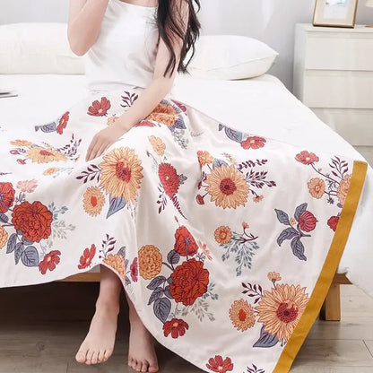 A multicolor gauze flower bath towel featuring a flowing white maxi skirt design with vibrant orange and red floral patterns and golden trim