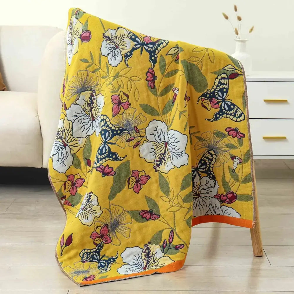 A vibrant yellow decorbites gauze flower bath towel with white pink and blue butterfly pattern for bedroom decor