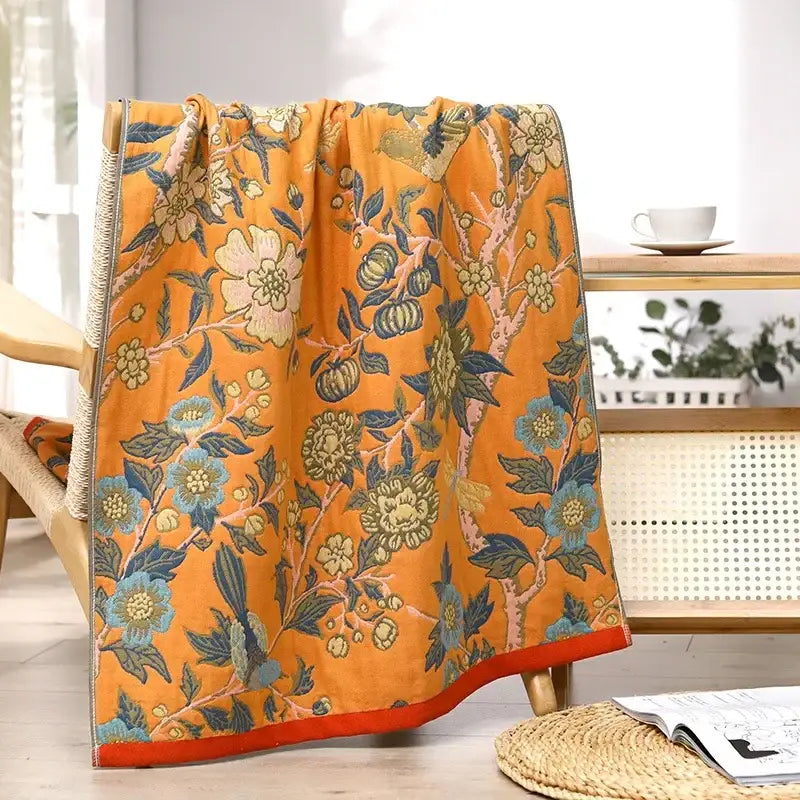 Vibrant orange decorbites gauze flower bath towel featuring intricate blue green and cream floral pattern on textured fabric