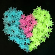 A collection of translucent blue pink and neon green stars glow dark wall stickers arranged in a heart shape