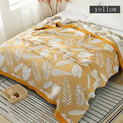 A soft yellow decorbites cotton gauze boho throw blanket with white leaf pattern and mustard border for living room decor