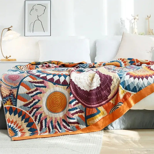 A multicolored cotton gauze boho throw blanket with intricate geometric patterns in orange purple blue and cream for decorbites