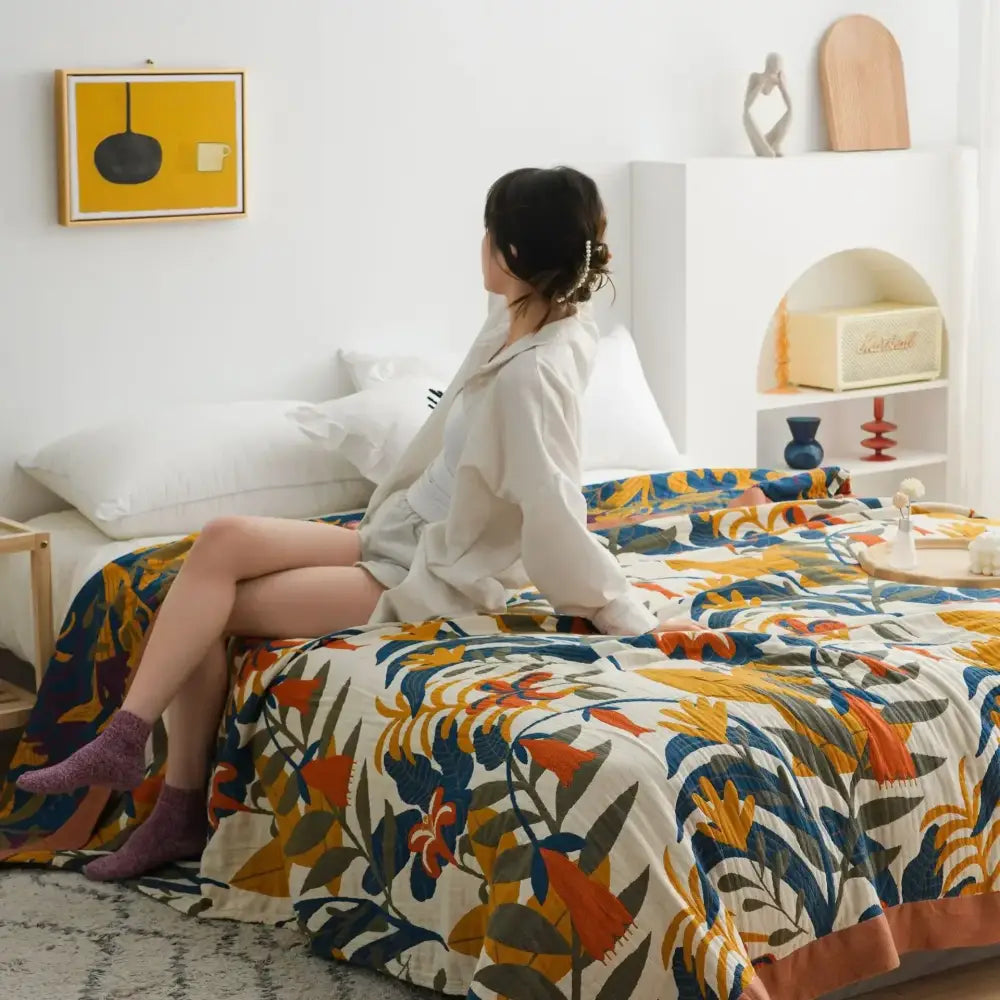 A vibrant multicolored cotton gauze boho throw with bold orange blue and green floral patterns on cream background