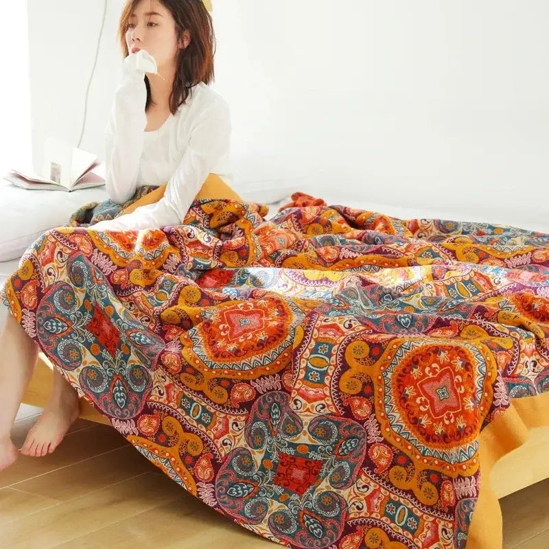 A multicolored cotton gauze boho throw blanket with vibrant mandala patterns in warm orange red and teal tones for decorbites decor