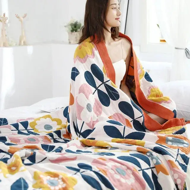 Multicolored cotton gauze boho throw blanket with vibrant pink yellow and navy floral pattern for bedroom or living room decor