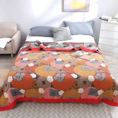 A cozy multicolored cotton gauze boho throw blanket featuring vibrant embroidered orange and pink pumpkins with gray flowers