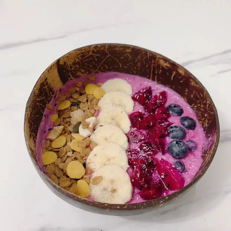 A vibrant pink smoothie bowl in a natural dark brown decorbites coconut bowl set handcrafted for kitchen use