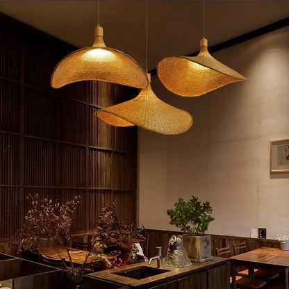 Three golden brown bamboo wicker chandelier pendant lights with a natural design hang over a dining room table