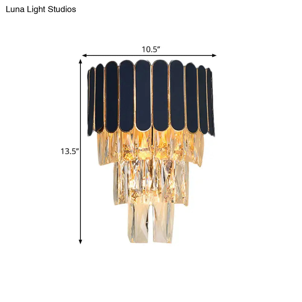 Elegant black and gold chandelier with cascading crystal tiers complementing navy and gold rectangle-cut crystal wall sconce for living room