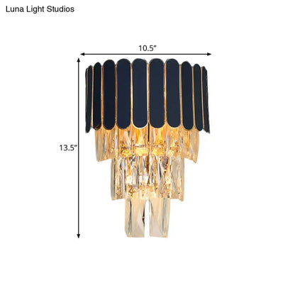 Elegant black and gold chandelier with cascading crystal tiers complementing navy and gold rectangle-cut crystal wall sconce for living room