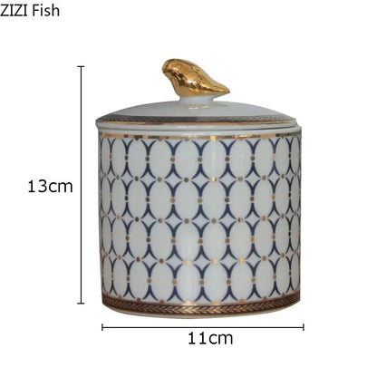 White ceramic storage jar with navy blue geometric pattern and gold plated bird decorbites gold plated topper