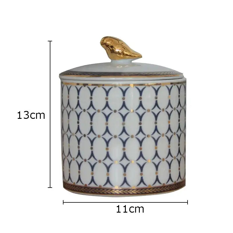 A white ceramic navy and white geometric storage jar with a gold plated bird lid for decorbites gold plated decor
