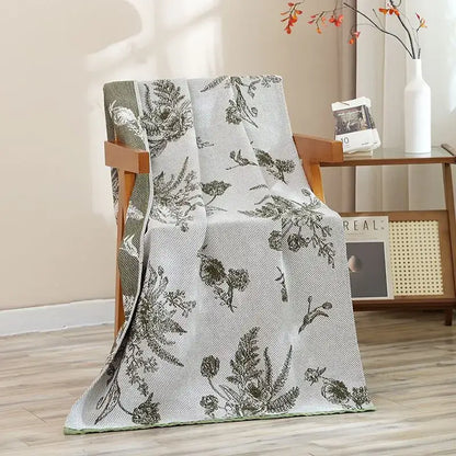 A light gray woven throw with dark green botanical pattern draped over a chair for decorbites cat bath towel use