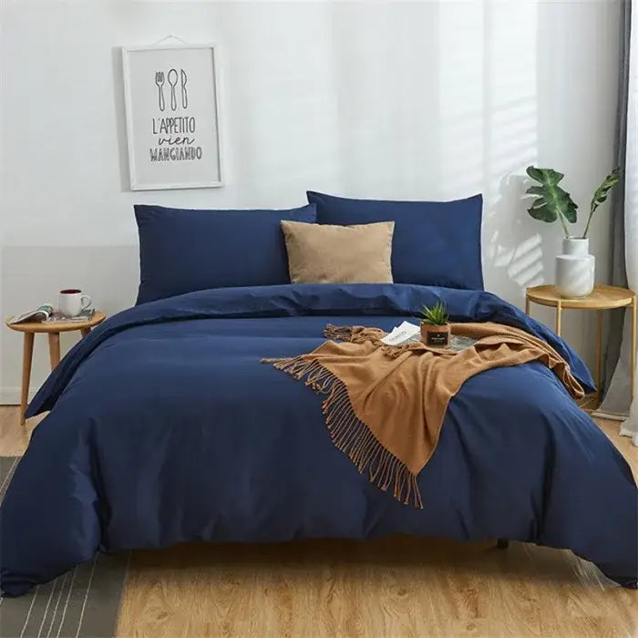 Navy blue solid color decorbites cotton 4pcs bedding set with matching pillowcases and tan throw blanket on bed