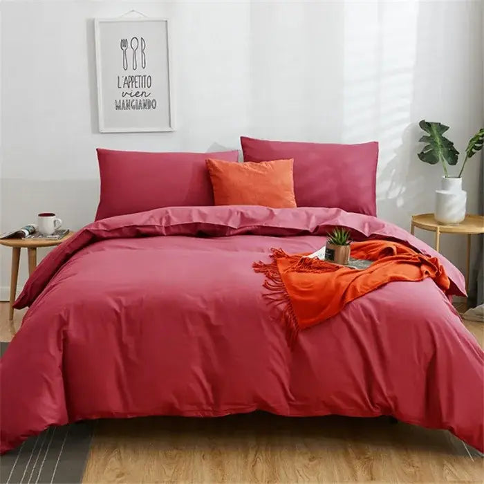 A plush deep red solid color decorbites cotton 4pcs bedding set with matching and orange accent pillows