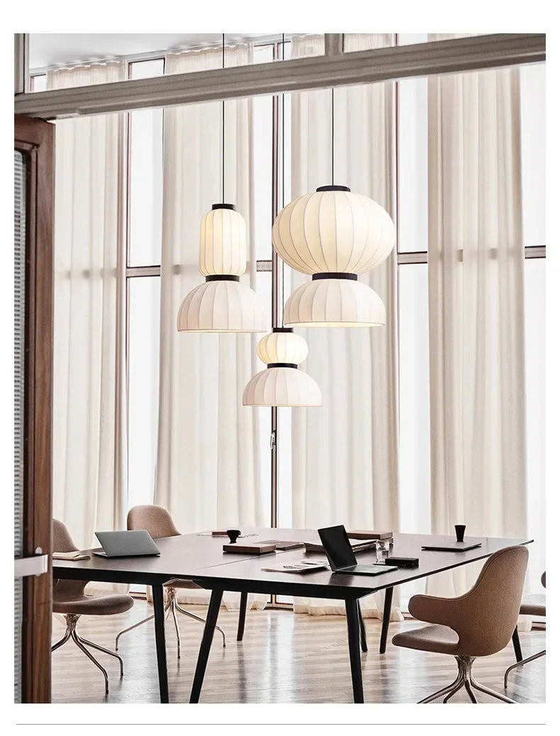 White pleated paper lantern light with black metal accents hanging in a dining room shop hanging light fixture