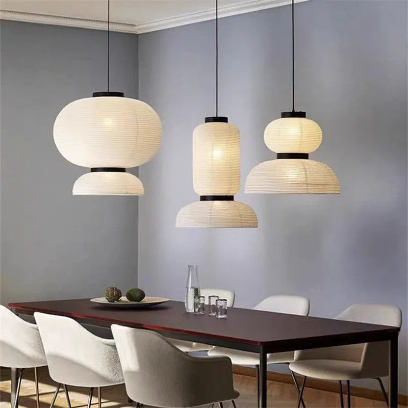 Three elegant off-white rice paper Noguchi lantern lights with black metal hang as dining room shop hanging light