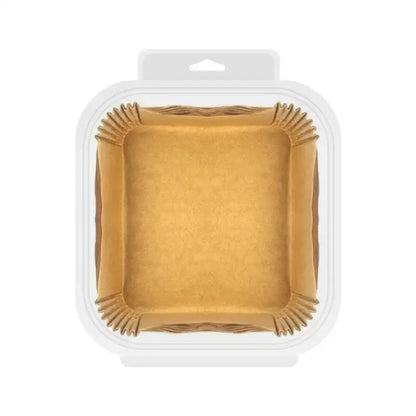 Square-shaped brown nonstick parchment paper liners with fluted edges packaged in a clear container for air fryer baking