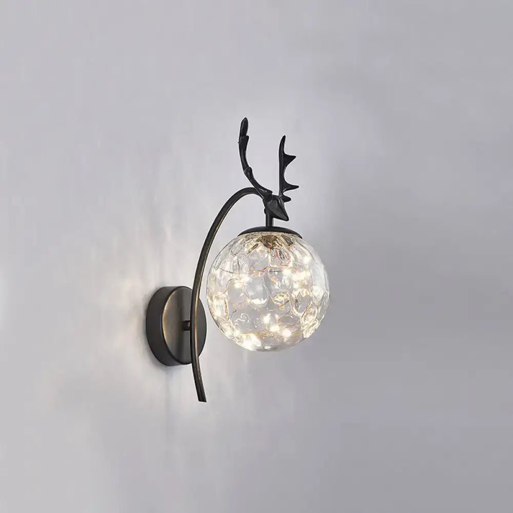 Antique bronze-finished nordic ball wall mount sconce with clear textured glass globe and deer antler detailing