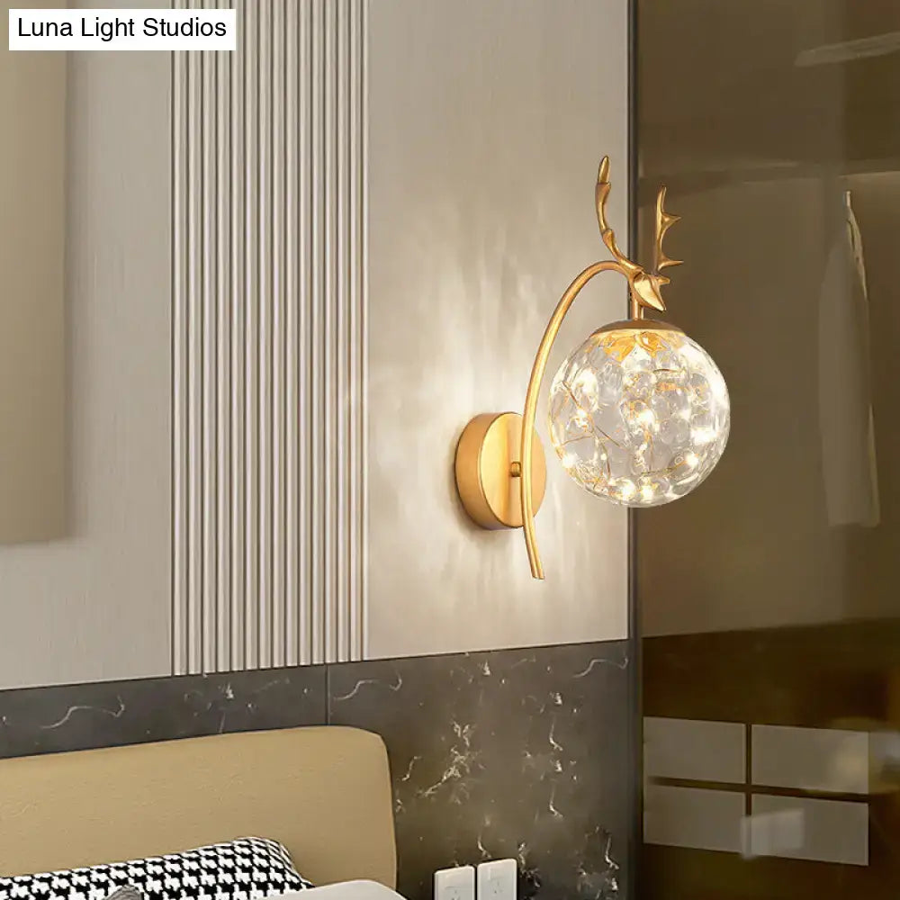 Gold-toned nordic ball wall mount sconce with black antler design and spherical glass globe filled with sparkling crystals