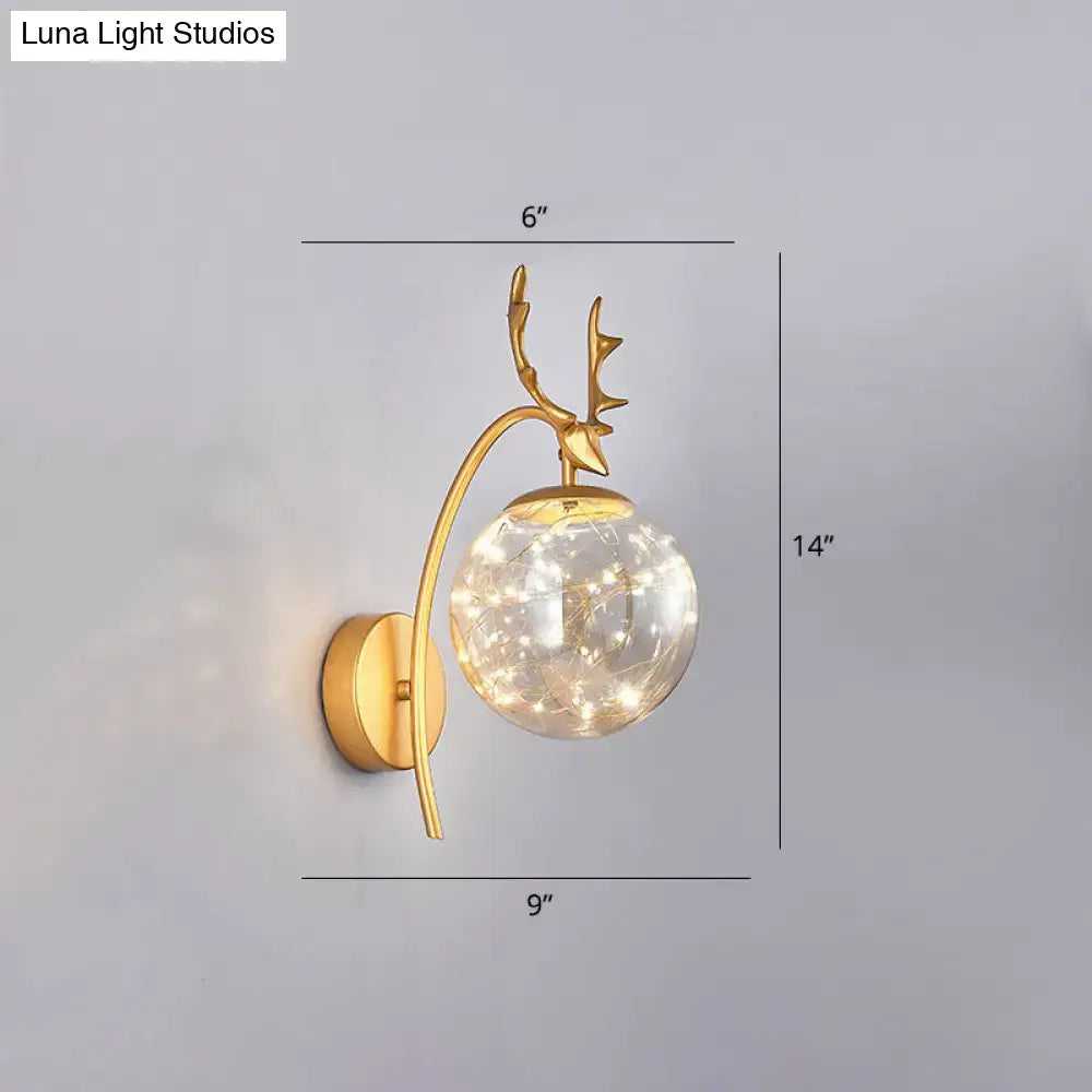 Gold-toned nordic ball wall mount deer antler sconce with spherical glass globe and warm fairy lights for bedroom use