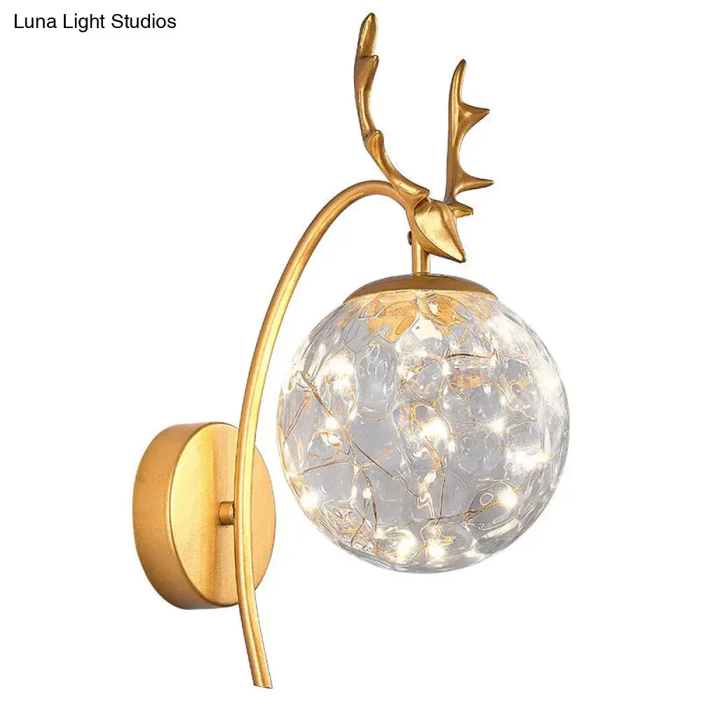 Gold-toned nordic ball wall mount deer antler sconce with crackled glass globe and warm led lights for bedroom use