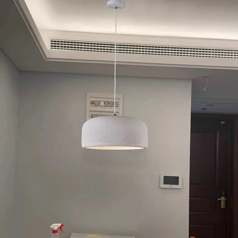 A modern white textured dome-shaped nordic led pendant lamp suspended by a thin cord for bar and restaurant lighting