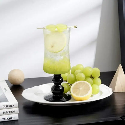Nordic black glass beaded stem goblet with slender black stem filled with green drink garnished with lemon and grapes