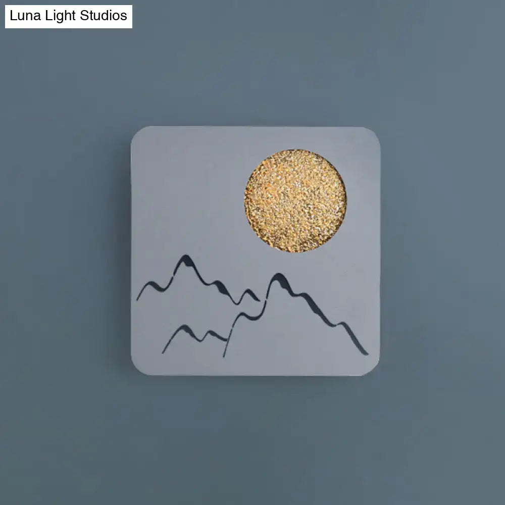 Modern black white grey wall light fixture with minimalist mountain and gold glitter sun on matte white surface for bedroom