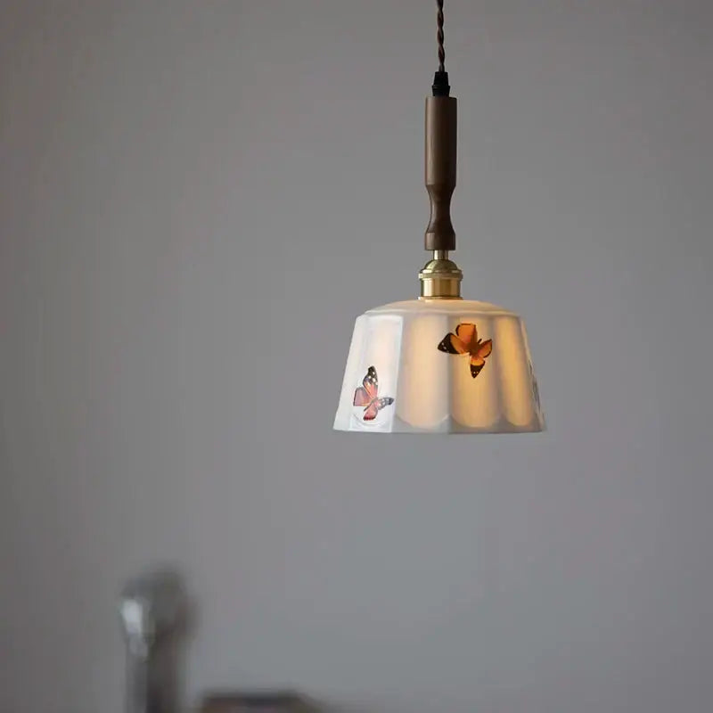 A delicate white ceramic pendant light with painted butterfly motifs and a brown wood led hanging rod for decorbites brown wood decor