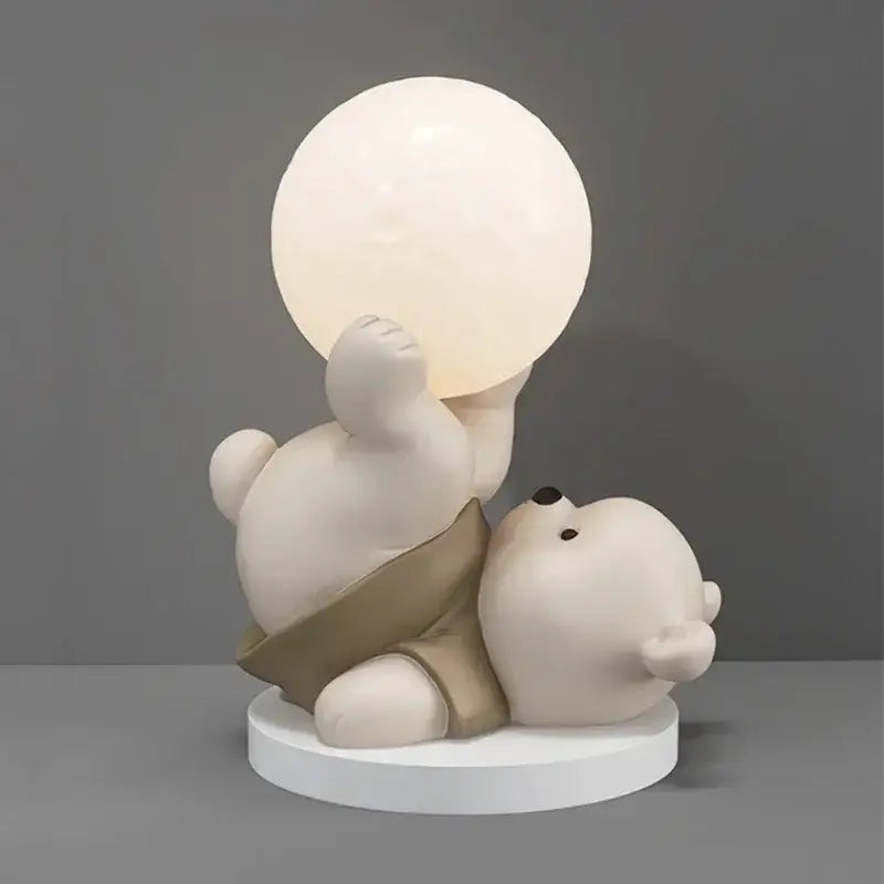 Cream-colored ceramic nordic bear table lamp with a glowing spherical light held by one bear and another resting beside it