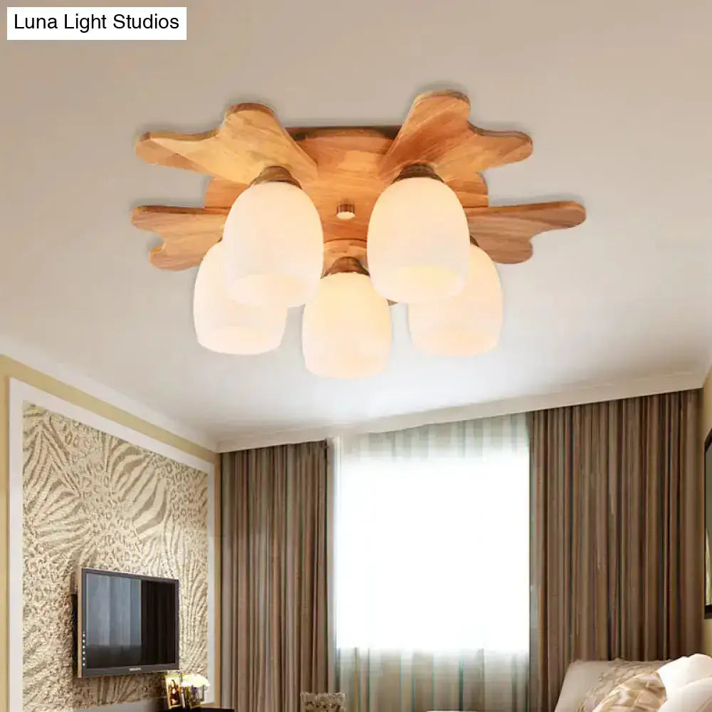 Wooden ceiling light with five cream glass bell shades and leaf-like wooden base for bedroom lighting