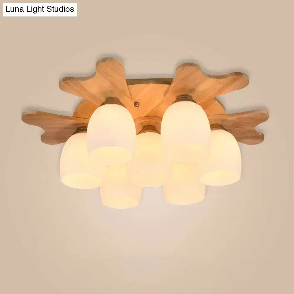 Wooden ceiling light with five cream glass bell frosted shades arranged in a starburst pattern for bedroom use