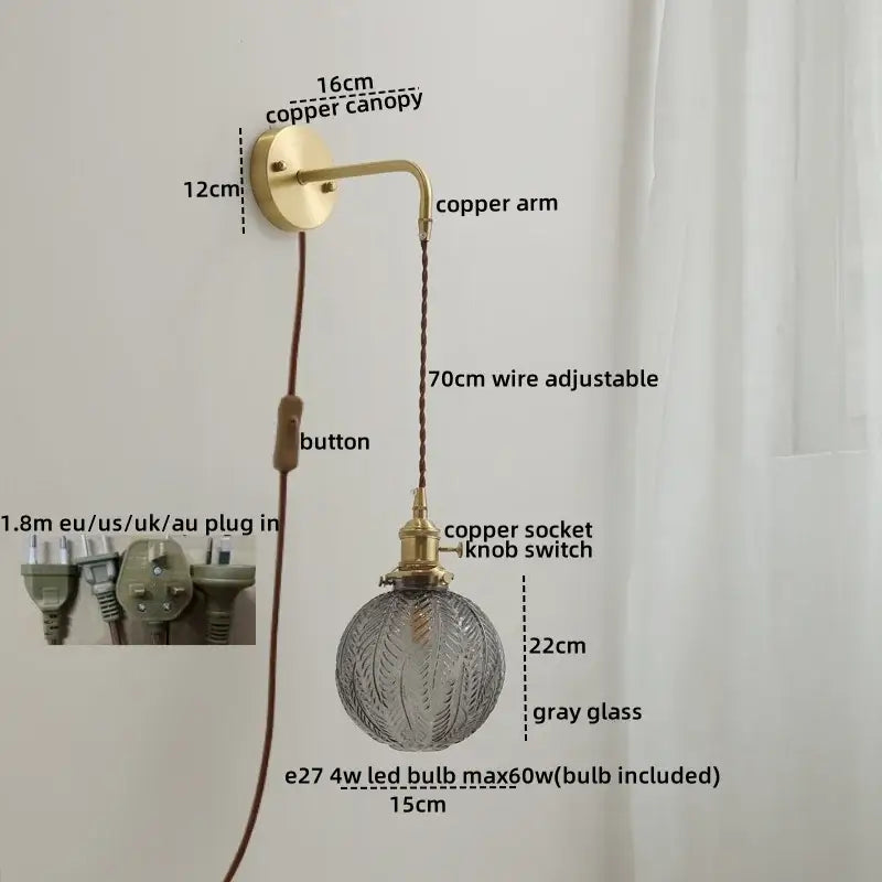 Vintage-style wall sconce lamp with brass-finished copper arm and gray etched glass globe on braided cord for bedroom
