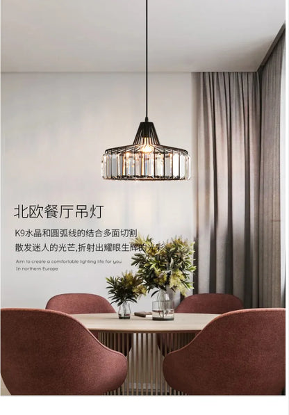 A modern nordic LED crystal pendant lamp with black iron frame and clear K9 crystal accents above dining table