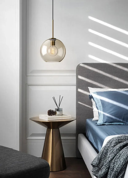 A sleek nordic led glass pendant light with a brass fixture and exposed filament bulb for dining room use