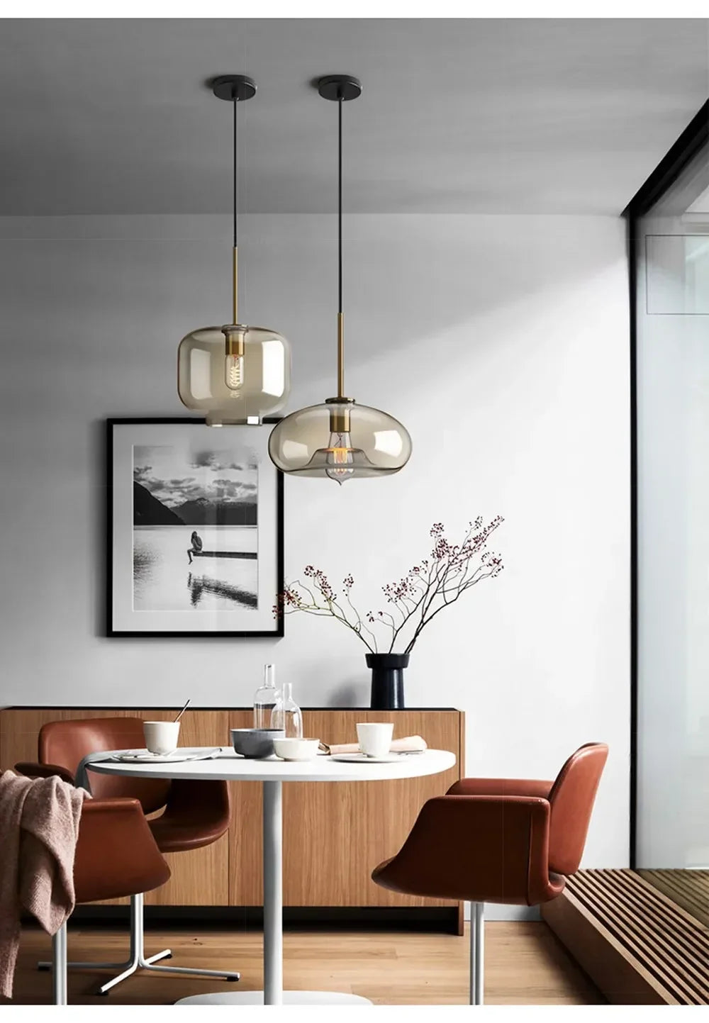 Two modern nordic led glass pendant lights with smoked glass shades and brass accents hang above a dining room table