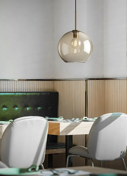 A nordic led glass pendant light with a smoked glass globe and brass accents above the dining room table