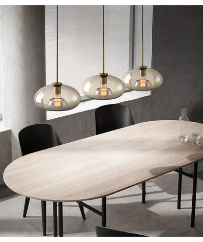 Three modern nordic led glass pendant lights with smoked glass globes and brass accents hang above a dining room table