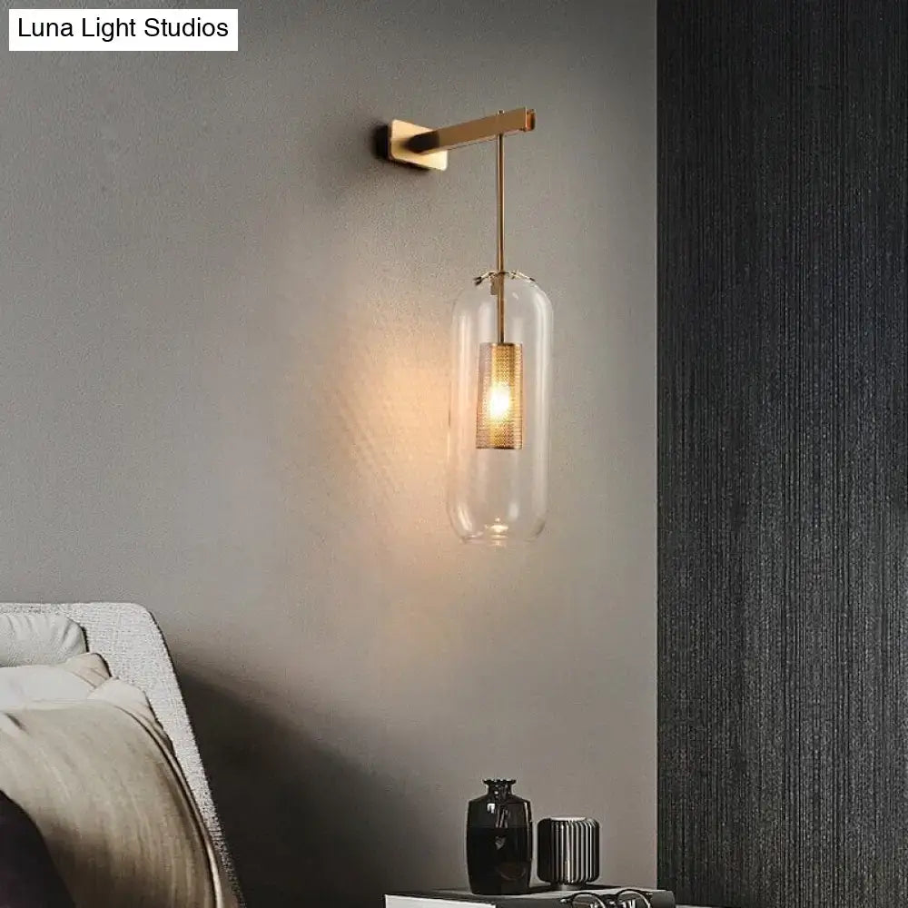 A nordic modern decor brass wall lamp with a clear glass lampshade and illuminated golden mesh filament bulb