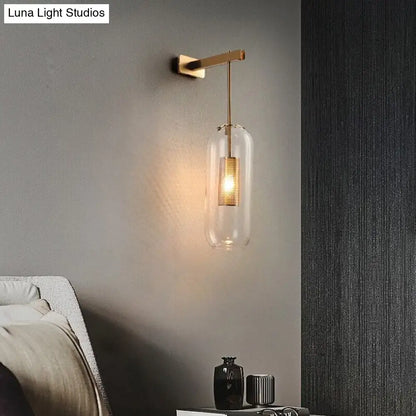 A nordic modern decor brass wall lamp with a clear glass lampshade and illuminated golden mesh filament bulb