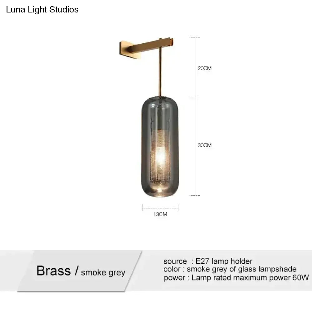 A nordic modern decor brass wall-mounted pendant light with a cylindrical smoke grey glass lampshade for bedroom
